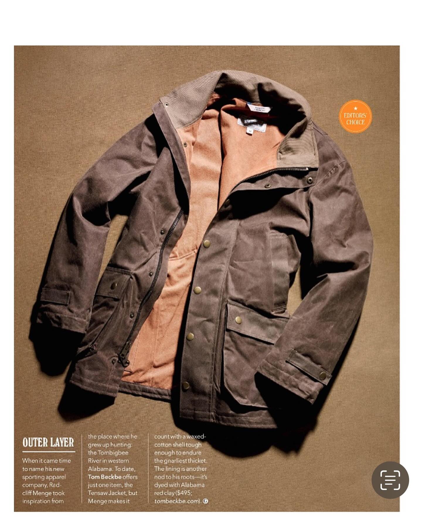 A brown and olive green jacket is laid flat on a beige background, showing its front side and slightly turned-up collar.