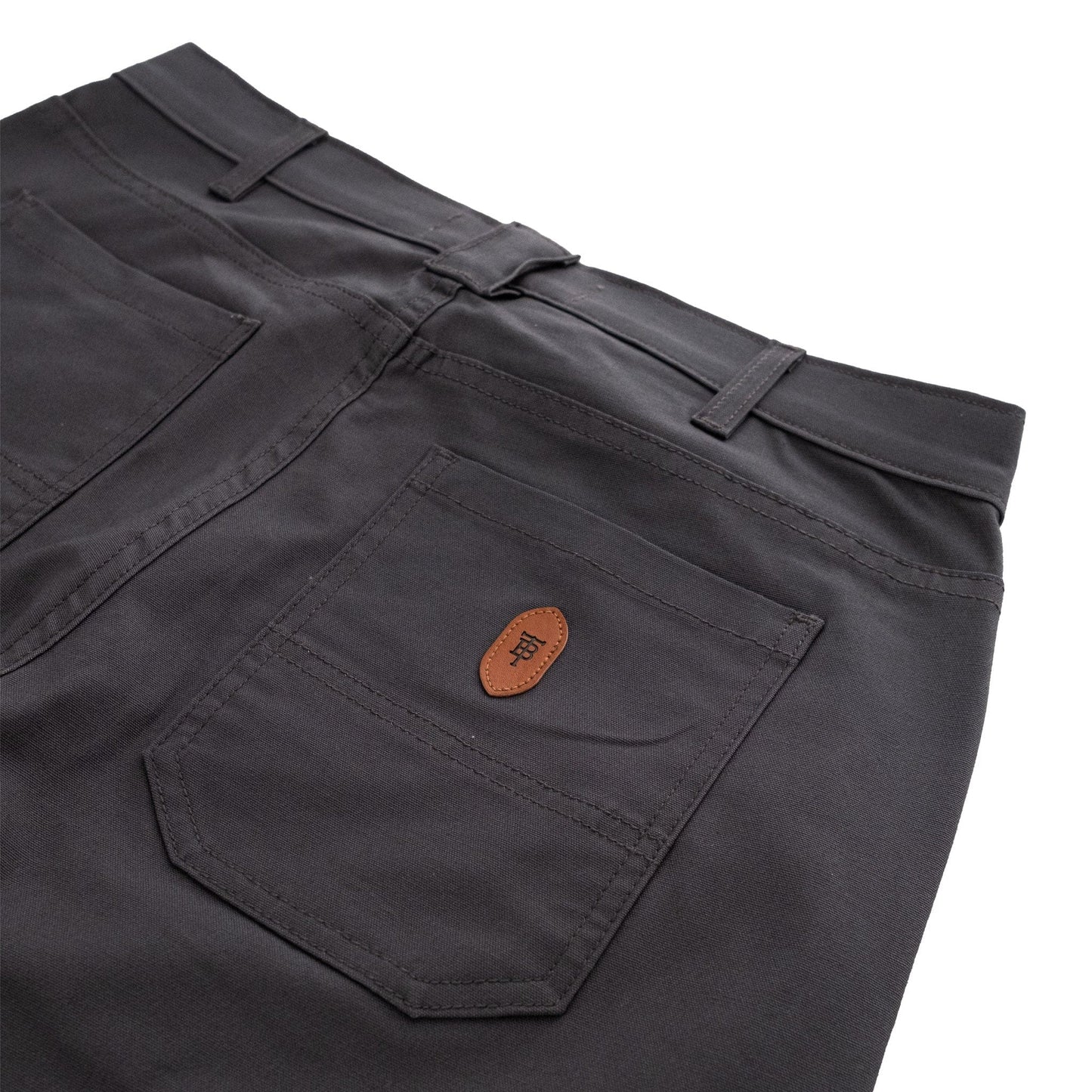The back view of Tom Beckbes Redmont Pant highlights a pocket with a leather patch, belt loops, and durable stitching.