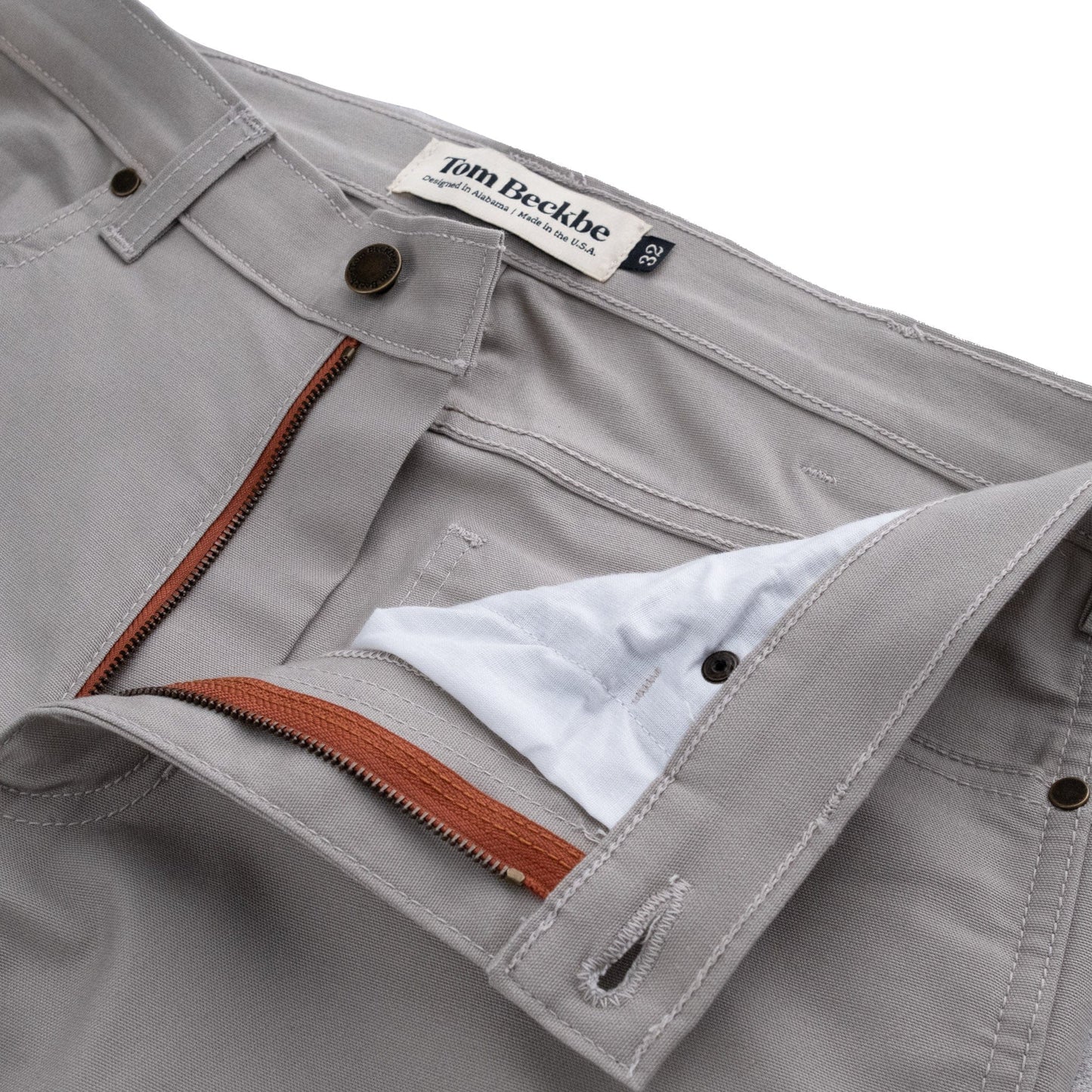 Gray Redmont Pant by Tom Beckbe features durable cotton, a visible zip fly, and a brown zipper pull.