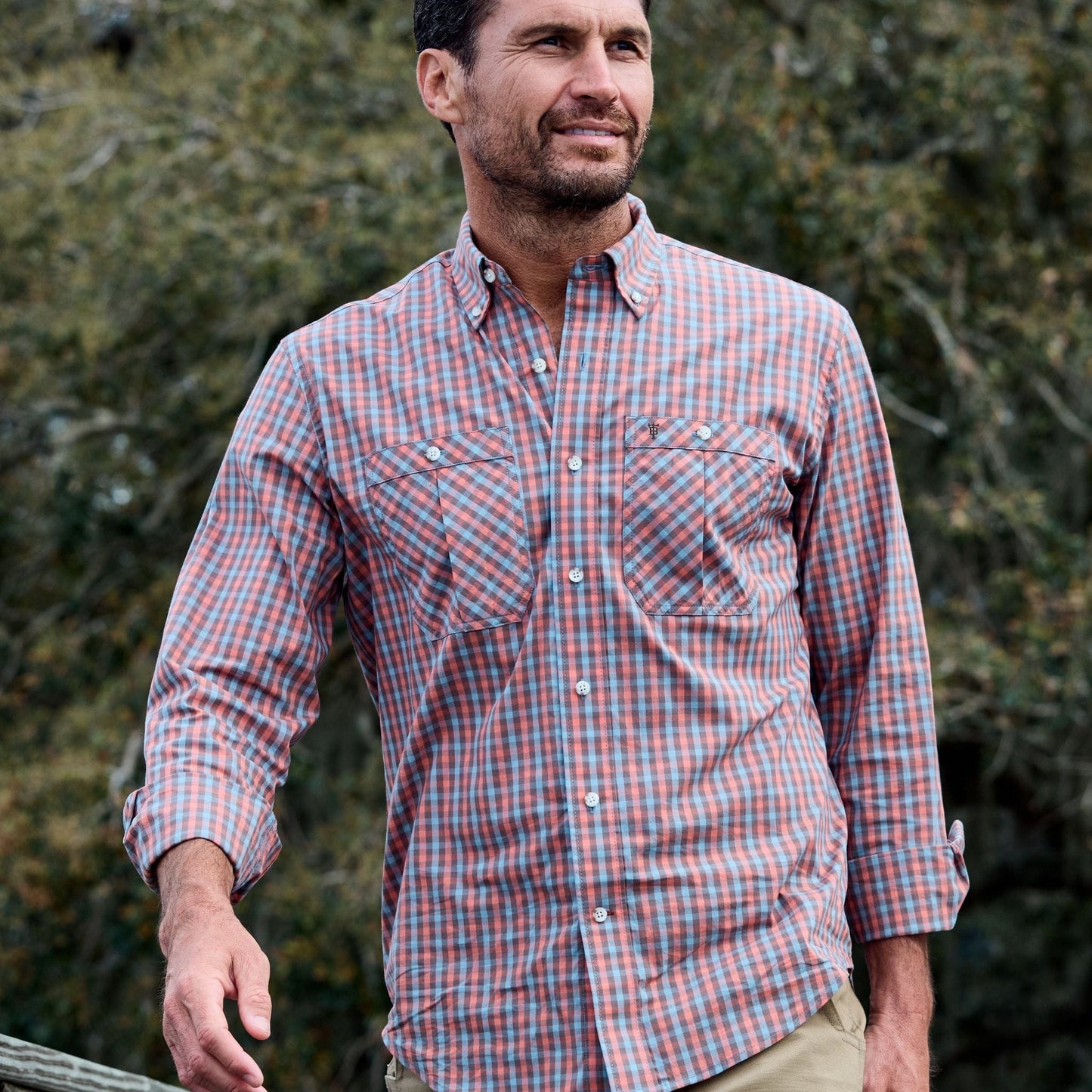 Man outdoors wearing a Tom Beckbe Tidewater Shirt, plaid, with trees in the background.