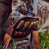 Open Tom Beckbes Classic Camo Blind Bag with double-shell pockets, revealing shotgun shells on grass and a dangling strap.