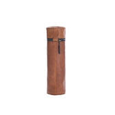 Tom Beckbes tall, cylindrical Leather Bottle Bag in full-grain leather stands upright with a vertical zipper.