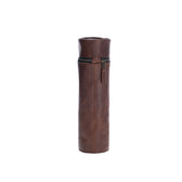 Tom Beckbes Leather Bottle Bag is a full-grain leather cylindrical case with a zipper, standing upright on white.