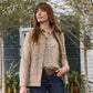 Woman outdoors in a tan vest and plaid shirt showcases the Tom Beckbe Crosshatch Quail Sterling Silver Belt Buckle.