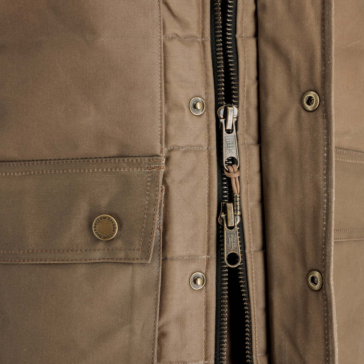 Close-up of the Tom Beckbe Fowler Vest: brown, weatherproof, metal buttons, zipper, and two fabric pockets.