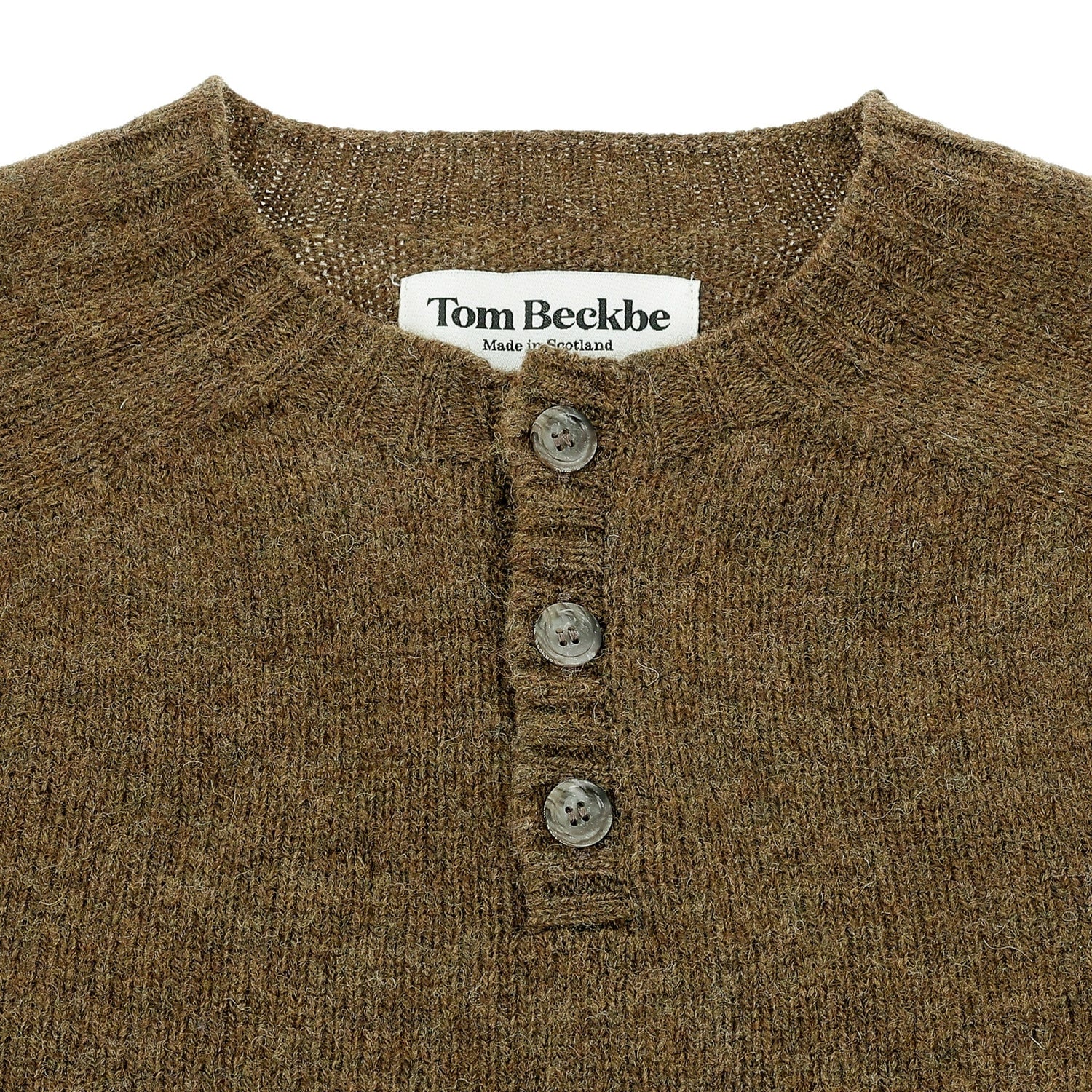Close-up of the Tom Beckbe Albemarle Henley Sweater in brown wool with three buttons and a label at the neckline.