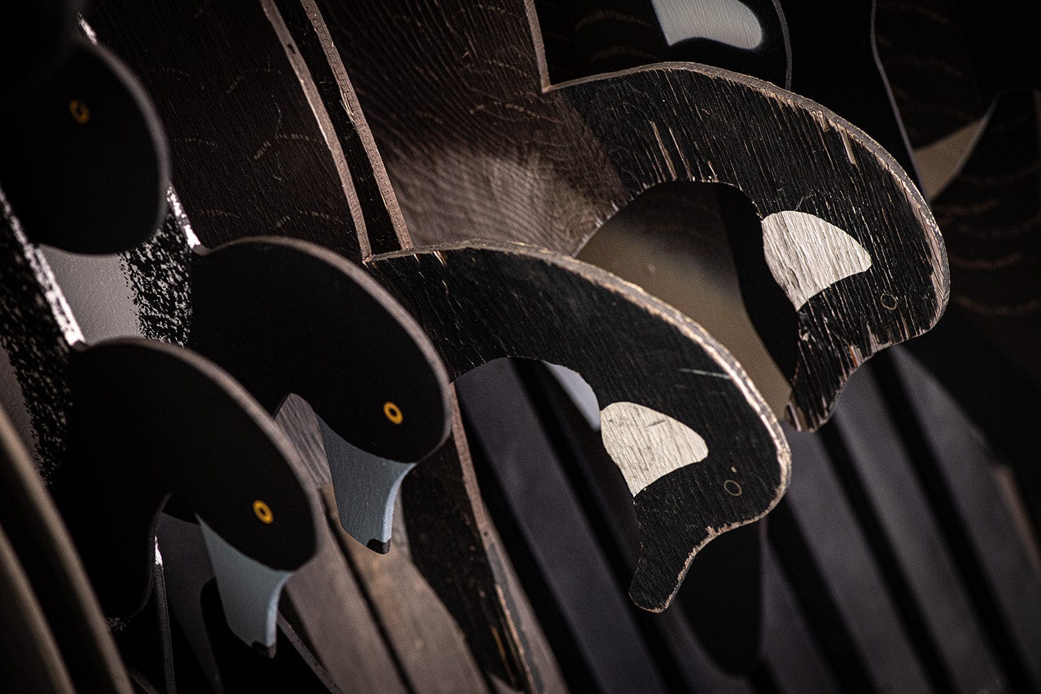 Close-up of several wooden cutouts shaped and painted like black birds with yellow eyes arranged in a row.
