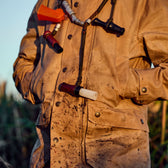 Person in a Tensaw Jacket by Tom Beckbe with hands in pockets, wearing multiple duck calls around their neck.