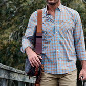Man walking on a pier wearing a tidewater shirt and carrying a fly fishing hip bag on his shoulder.
