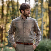 A man wears the Tom Beckbe Dixon Brushed Cotton Twill Shirt and khaki pants outdoors, hands in pockets, with trees behind.