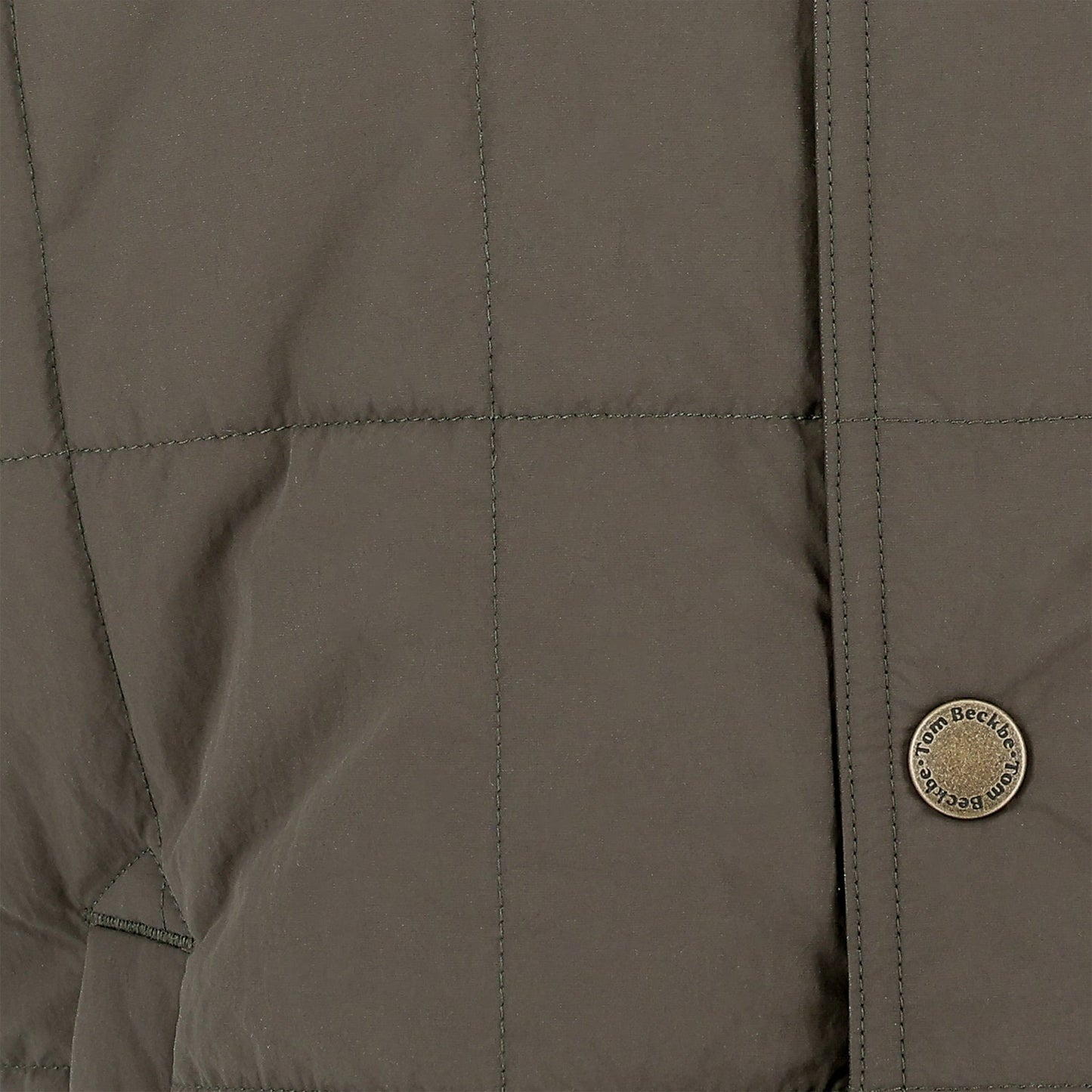 Close-up of the Tom Beckbe Burgess Quilted Vest in khaki, with visible stitching and a branded round metallic button.