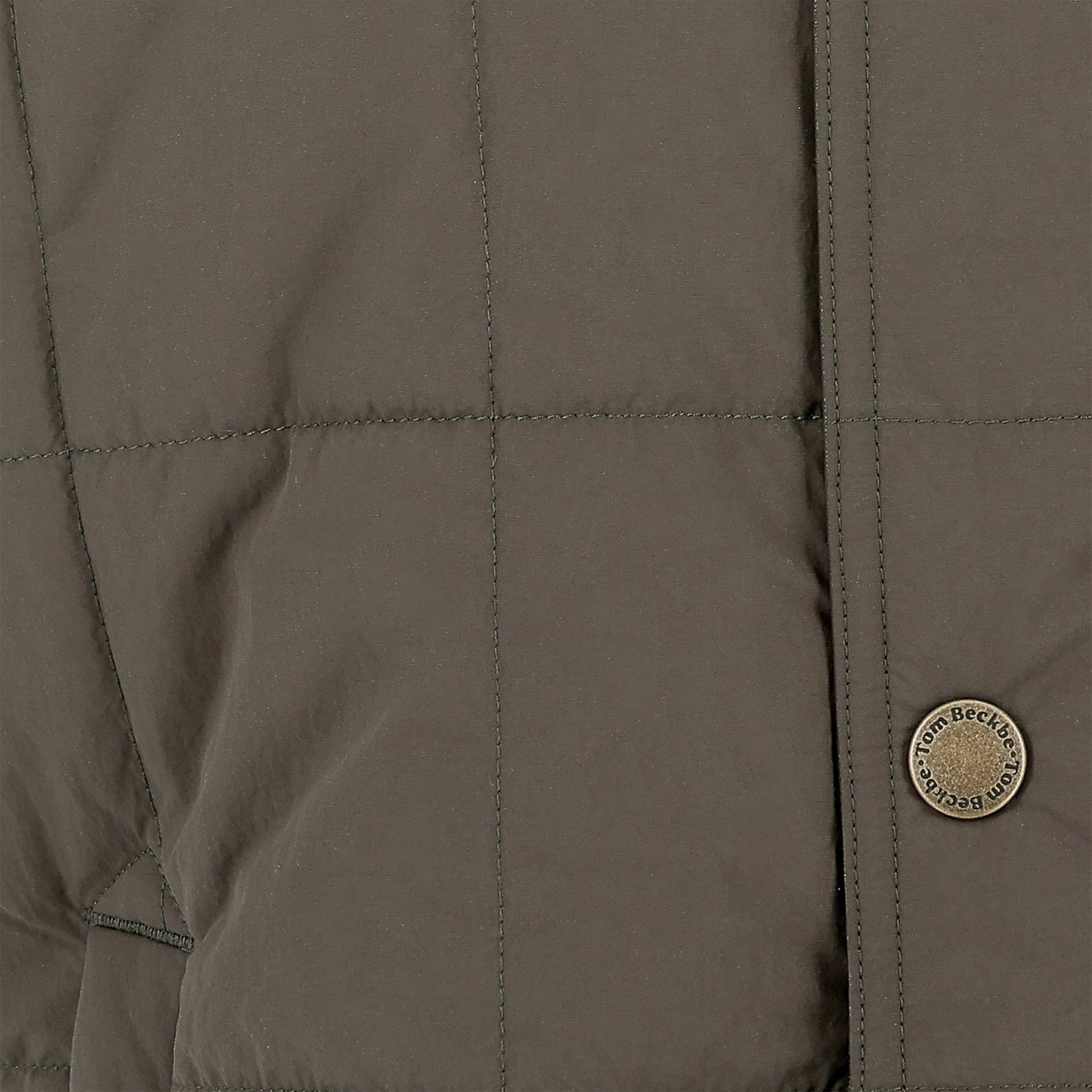 Close-up of the Tom Beckbe Burgess Quilted Vest in khaki, with visible stitching and a branded round metallic button.