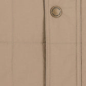 Close-up of the Tom Beckbe Burgess Quilted Vest in beige featuring detailed stitching and signature button.