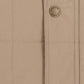 Close-up of the Tom Beckbe Burgess Quilted Vest in beige featuring detailed stitching and signature button.
