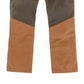 A close-up of Tom Beckbe's Burwell Brush Pant features brown fabric below the knees and dark gray above with a diagonal seam.