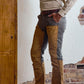 A man in Tom Beckbe’s Burwell Brush Pant and long-sleeve shirt stands by a textured, exposed brick wall.