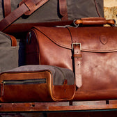 Tom Beckbe Canvas Dopp Kits with waterproof liners are displayed, showcasing their buckles on a wooden surface.