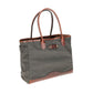 The Tom Beckbe Canvas Tote is durable, featuring green canvas, brown leather handles, a front pocket, and a reinforced bottom.