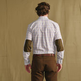 Man in a checkered shirt with dark elbow patches and brown pants standing with his back to the camera.