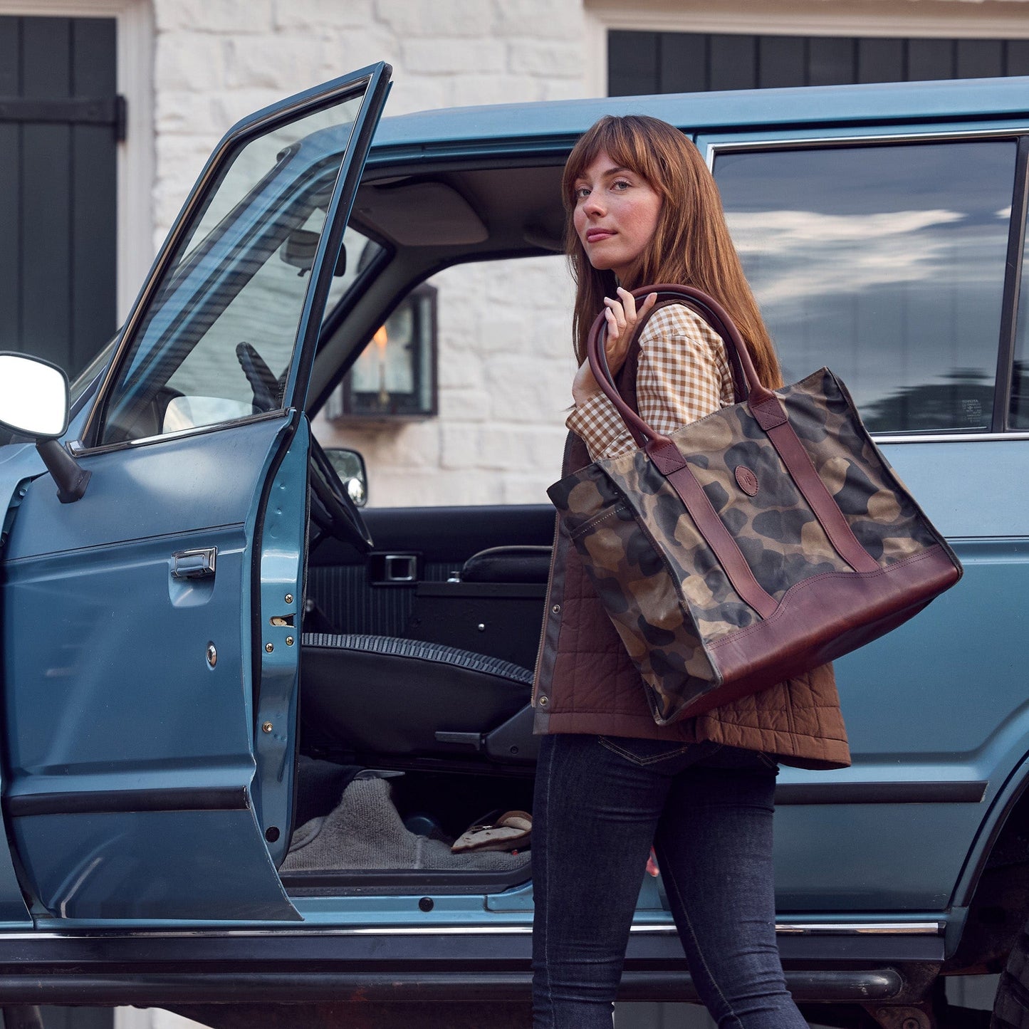 A woman carrying the Tom Beckbe Classic Camo Carryall Bag out of a car.