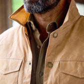 A man with a gray beard wears the Tom Beckbe Chatom Jacket over a brown button-up shirt with the collar popped.