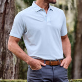 Man in a Tom Beckbe Coastal Polo Shirt and dark pants, standing outdoors with trees in the background.