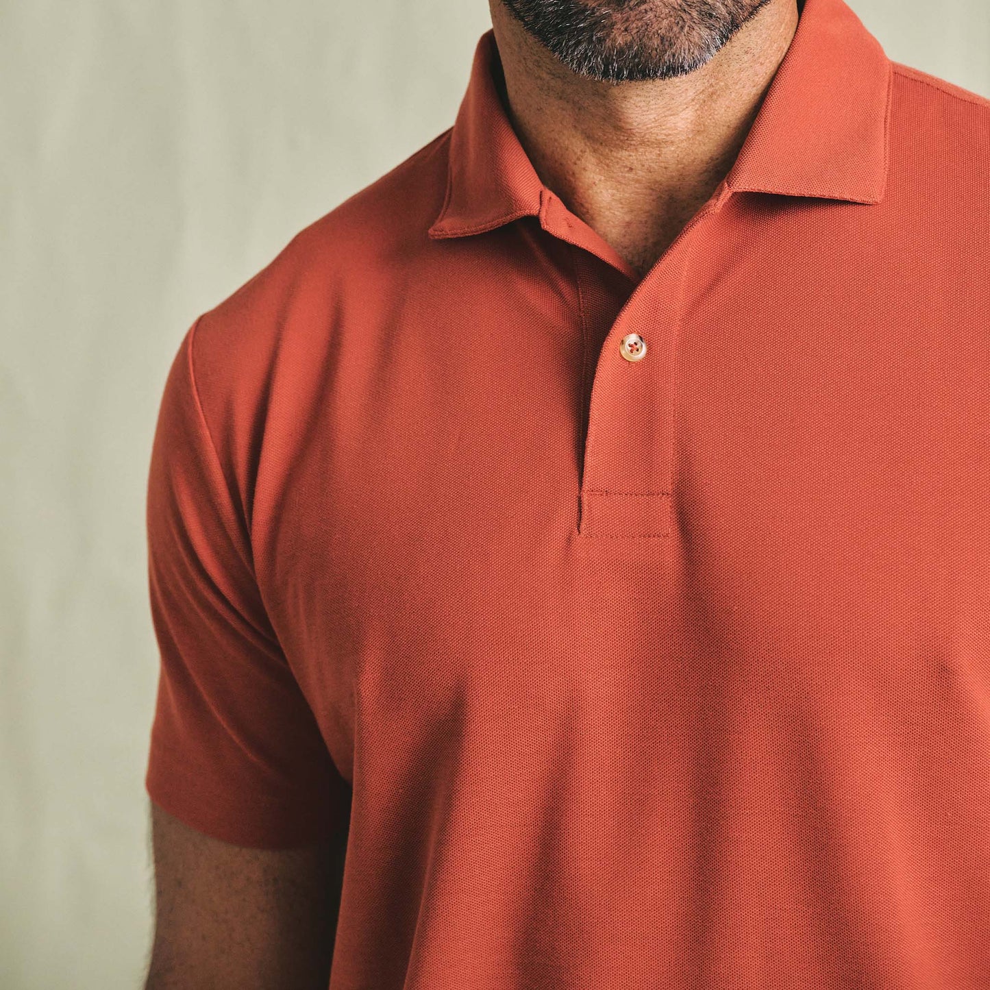 Man wearing a Tom Beckbe Coastal Polo Shirt in rust, shown from shoulders to mid-torso against a plain background.