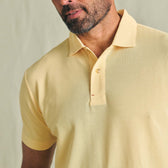 A man wearing a light yellow Tom Beckbe Coastal Polo Shirt against a neutral background.