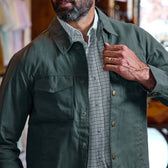 Man wearing Tom Beckbe Crawford Jacket over a plaid shirt, touching his chest and displaying a gold wedding ring.