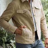 A man wears the Tom Beckbe Crawford Jacket with snap buttons and chest pockets, one hand in his pocket.