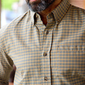 Man wearing Tom Beckbes Culver Oxford Shirt—a beige and blue check cotton shirt with front pocket, shoulders down view.
