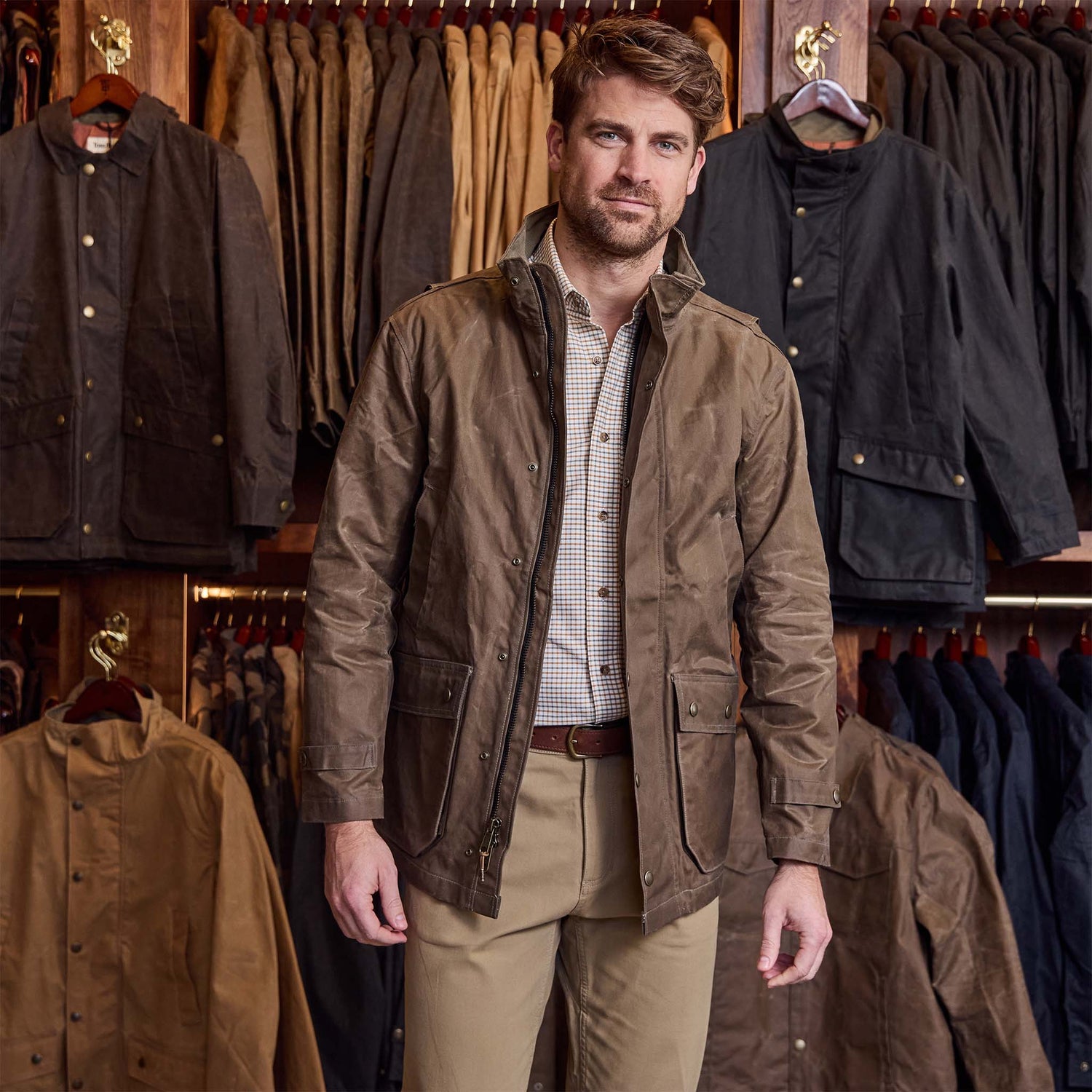 A man stands in a store with Tom Beckbe Culver Oxford Shirts hanging on racks behind him.