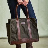 Person holding the Tom Beckbe DU Canvas Carryall, a large olive green tote with brown leather handles.