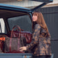 Woman in a camo jacket loads a Tom Beckbe DU Canvas Carryall into the open trunk of a car.