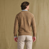 Man faces away in a Tom Beckbe Dalton Crewneck Sweater and light pants, set against a beige backdrop.