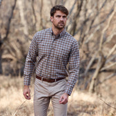 Man wearing a Tom Beckbe Dixon Brushed Cotton Twill Shirt and khaki pants standing outdoors in a dry, wooded area.