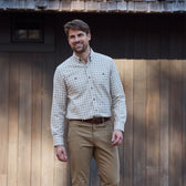 Man wearing the Tom Beckbe Dixon Brushed Cotton Twill Shirt and khaki pants smiles in front of a wooden building.