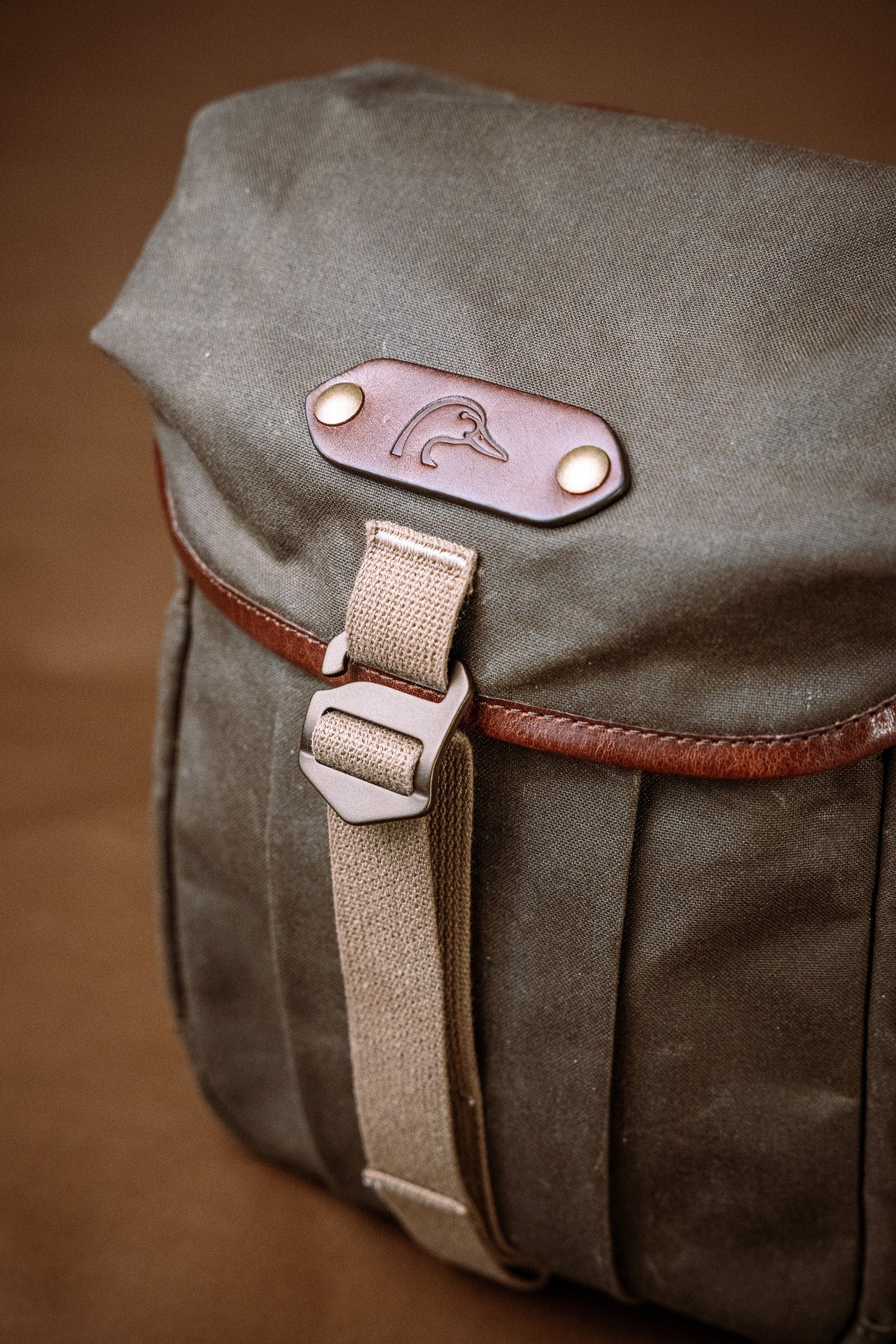 Brown leather bag with strap and metal buckle on a brown background