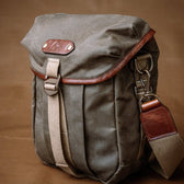 The Tom Beckbe DU Timber Bag, waxed cotton canvas with leather strap, sits on a brown background.