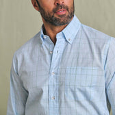 Man wearing the Tom Beckbe Ensley Pinpoint Oxford Shirt in light blue, long-sleeve with a chest pocket, facing sideways.