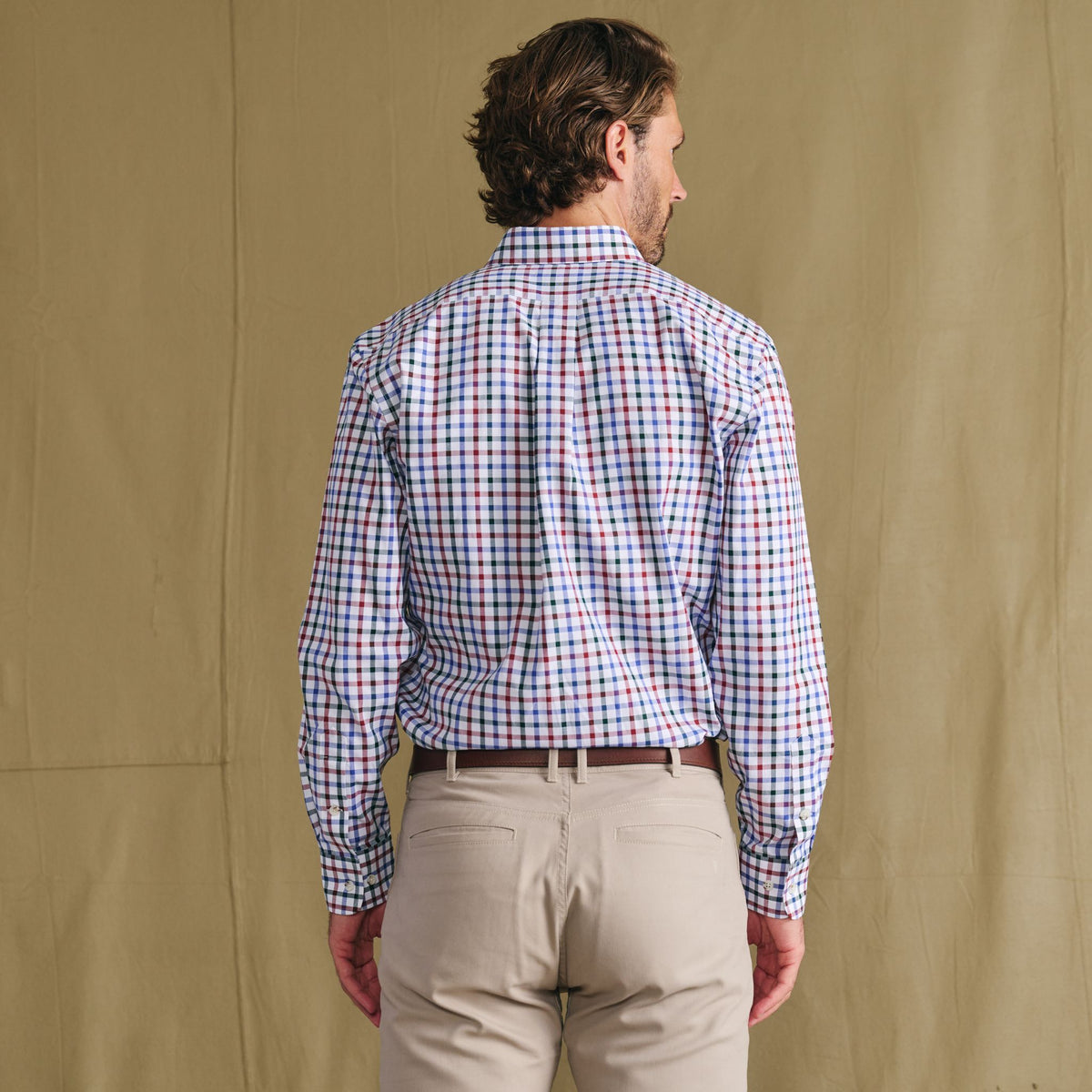 Man facing away in a Tom Beckbe Ensley Pinpoint Oxford Shirt, beige pants, on a plain tan background.