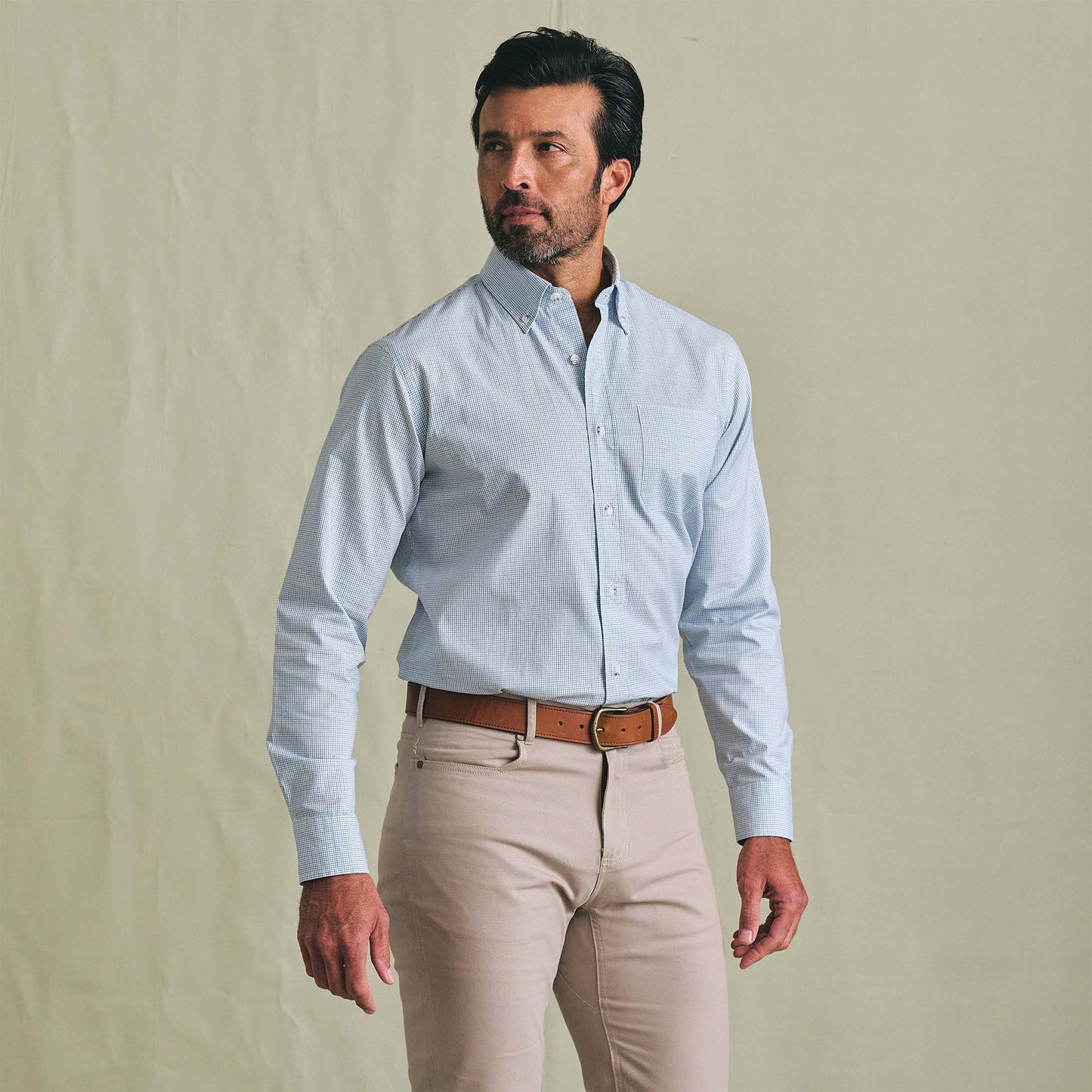 Man in a Tom Beckbe Ensley Pinpoint Oxford Shirt stands against a plain background, looking to the side.