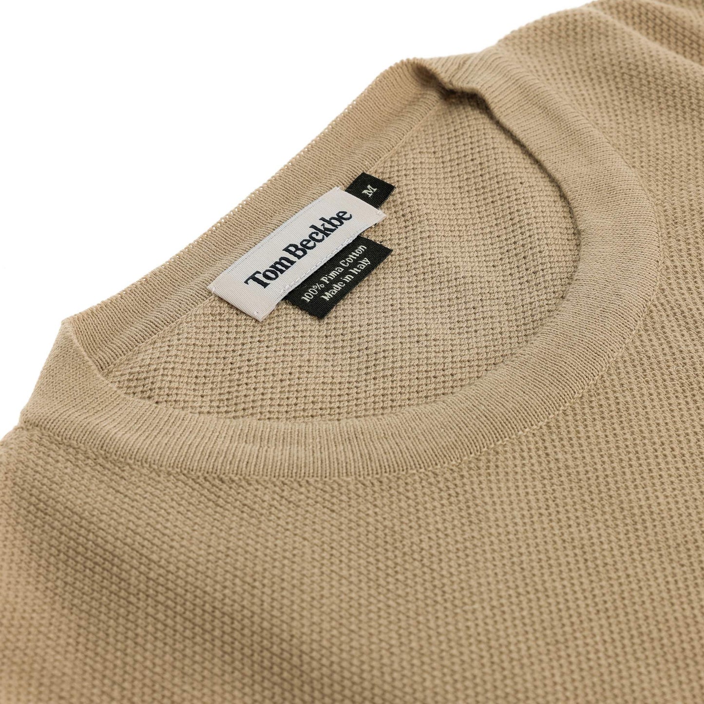 Close-up of a beige Foley Pima Crewneck Sweater with Tom Beckbe label sewn inside the collar.