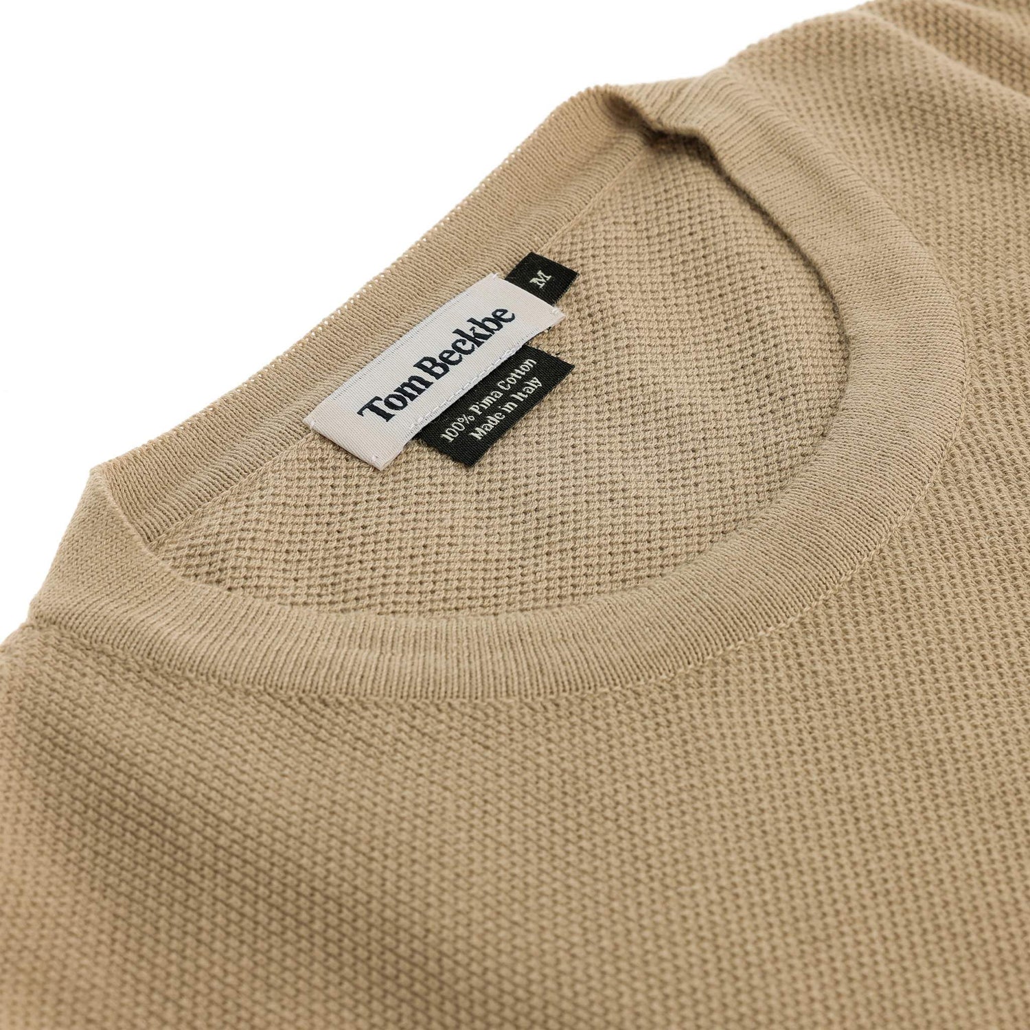 Close-up of a beige Foley Pima Crewneck Sweater with Tom Beckbe label sewn inside the collar.