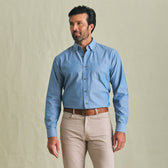 A man wears the Tom Beckbe Hanover Chambray Shirt with beige pants against a plain light background.