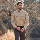 Man wearing a Tom Beckbe Hartwell Moleskin Shirt and dark pants, walking outdoors in a wooded area.