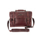 Brown leather satchel with a top handle, front buckle straps, and an adjustable shoulder strap against a white background.