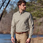Man wears a Tom Beckbe Knapp Cotton Twill Shirt and khaki pants outdoors by water and trees.