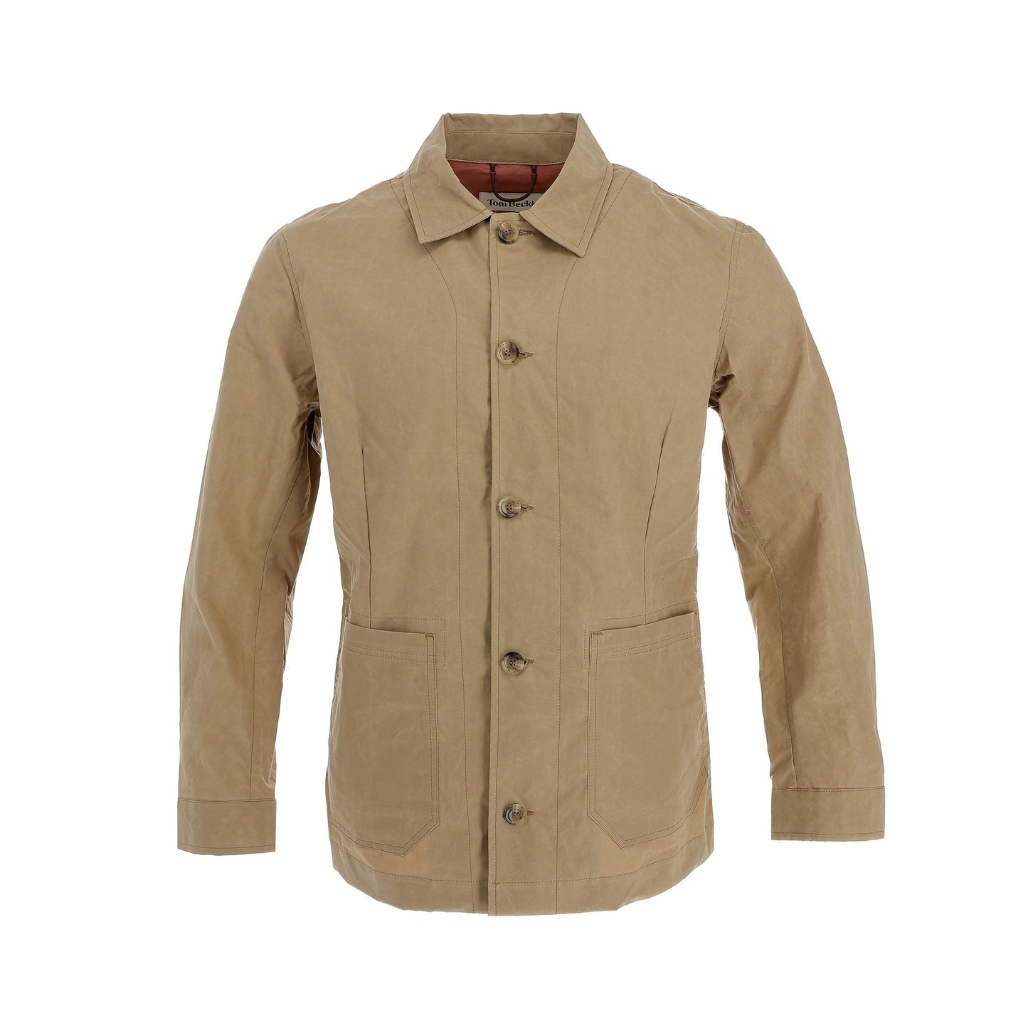 The Livingston Jacket by Tom Beckbe is a tan, long-sleeve safari jacket with front button closure. It has two large lower front pockets and a pointed collar, featuring a minimalist design without visible branding.