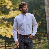 Man strolls outdoors in a Tom Beckbe Monroe Poplin Shirt and trousers, with greenery in the background.